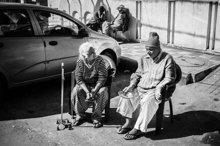 An elderly couple on plastic chairs on a Delhi street