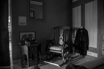 An empty rocking chair, a coat still hanging beside it